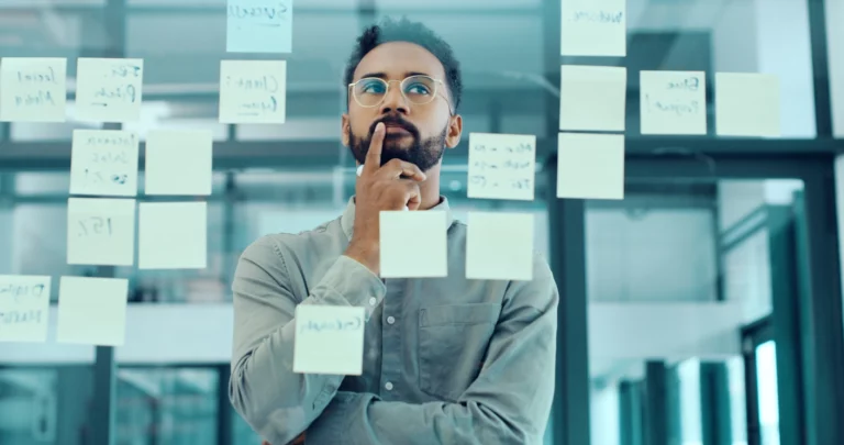 Thoughtful professional reviewing notes on a glass wall, reflecting on complex decisions and ethical considerations in compliance and risk management.